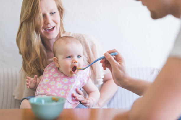 istock Two Caucasian parents feed their infant daughter at the table. 897803504