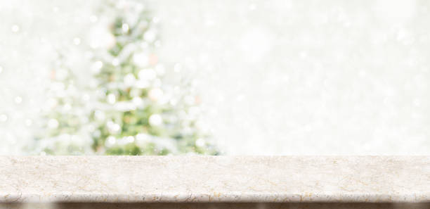 istock Empty cream marble table top with abstract muted blur christmas tree and snow fall background with bokeh light,Holiday backdrop,Mock up banner for display or montage of product 897805858