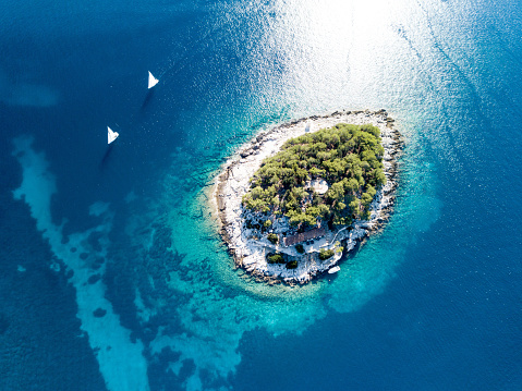 two sailboats navigates near a small island at sunny adriatic sea