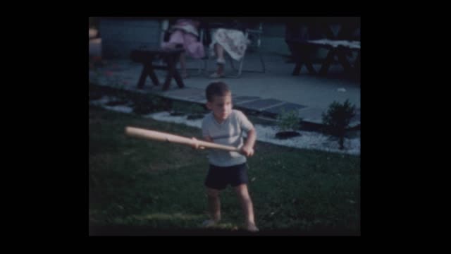 Family plays with little boy with bat and big yellow ball