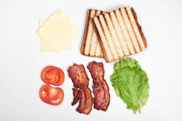 istock Ingredients for making sandwich. fresh vegetables, tomatoes, bread, becon, cheese. Isolated on white background, top view, copy space 897829542