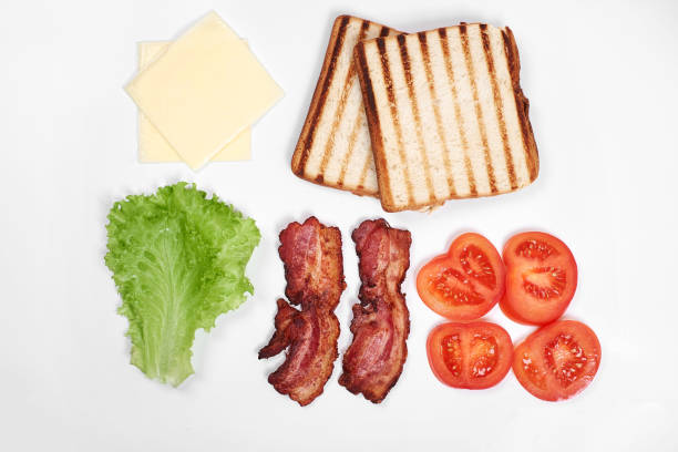 istock Ingredients for making sandwich. fresh vegetables, tomatoes, bread, becon, cheese. Isolated on white background, top view, copy space 897829586