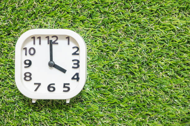 istock Closeup white clock for decorate in 4 o'clock on green artificial grass floor textured background with copy space 897834914