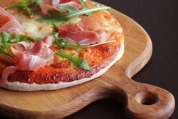 istock Pizza with smoked ham and rucola on dark background 897880184
