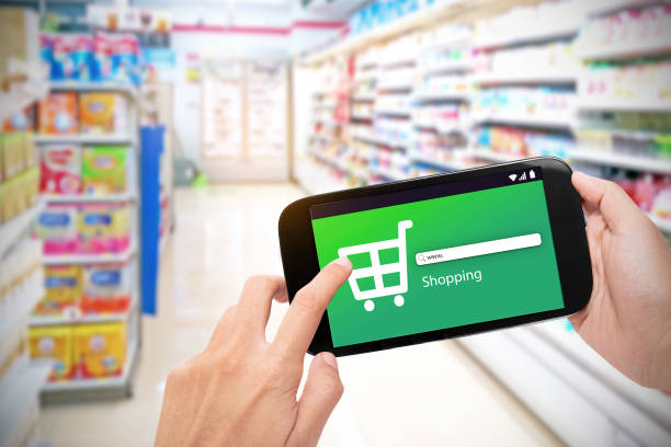 istock Hand holding mobile phone at supermarket checkout background 897884834