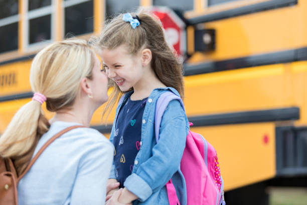 Loving mom sends adorable daughter off to school Mom gives daughter eskimo kiss before the girl boards school bus. The girl is excited about her first day of kindergarten. The school bus is in the background. first day of school stock pictures, royalty-free photos & images
