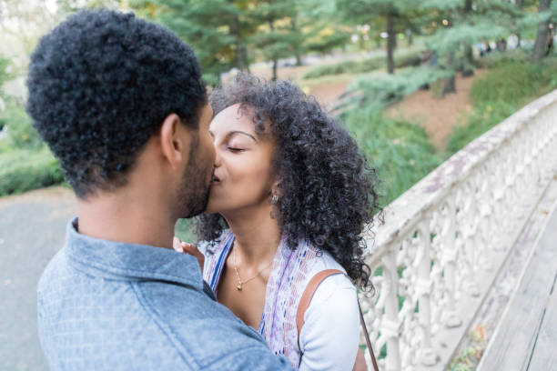 istock Young mixed race couple kiss while on romantic outdoor date 897885592