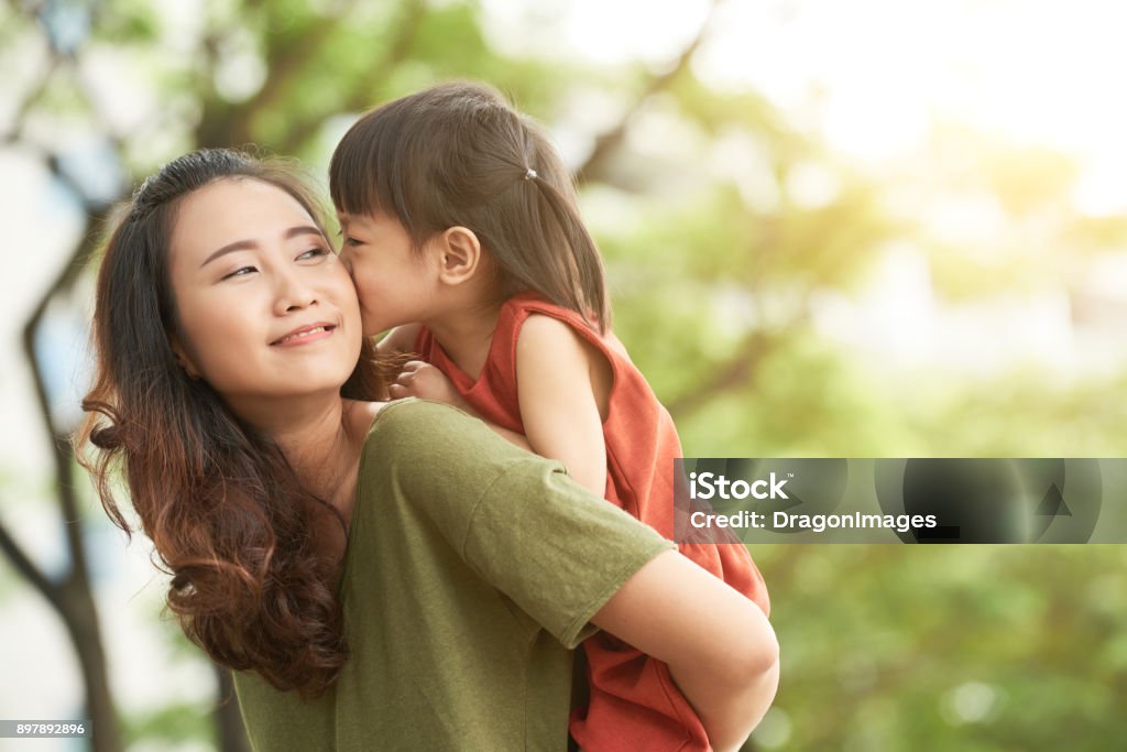 Spending time with mother Girl kissing mother when she giving her piggyback ride Mother Stock Photo