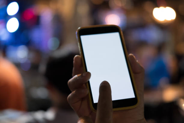 istock hand holding smartphone in pub. mobile phone with blank screen in restaurant 897896038