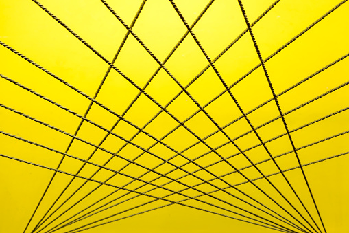 Crossing ropes create an abstract pattern on yellow and white background