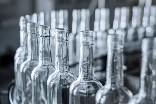 Empty glass bottles on the conveyor. Factory for bottling alcoholic beverages. Production and bottling of alcoholic beverages.