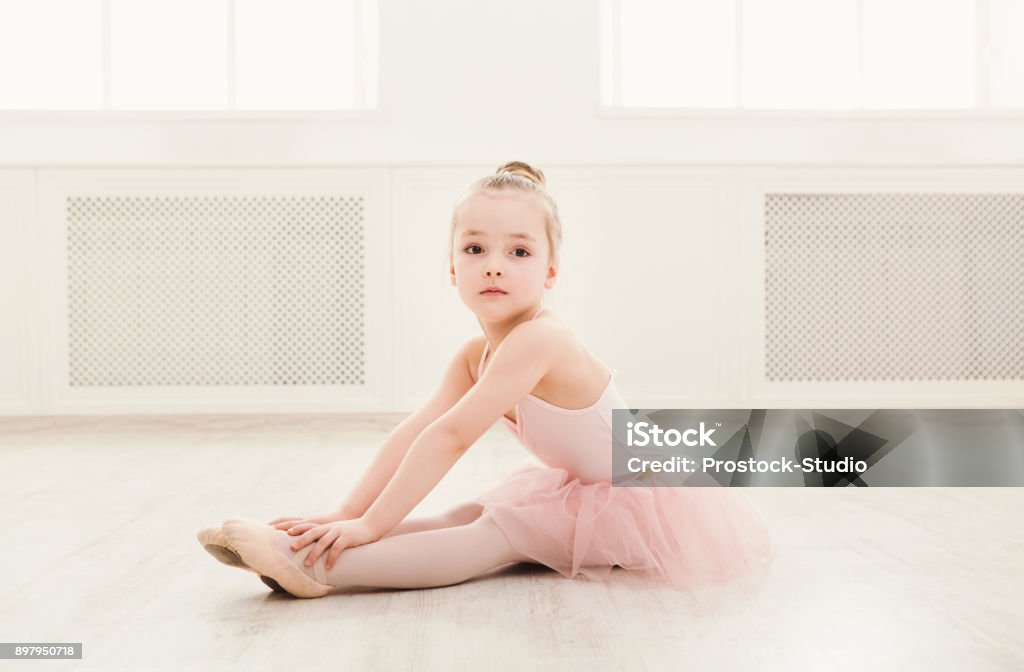 Portrait of little ballerina on floor, copy space Portrait of little ballerina on floor, copy space. Smiling baby girl dreaming to become professional ballet dancer, classical dance school Ballet Stock Photo