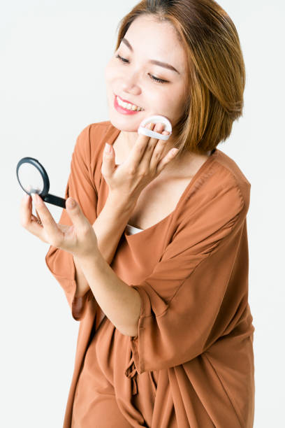 istock young woman applying powder compact against white background 897950940