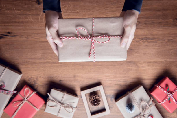istock Man Hands holding craft paper gift box on table wood decoration. 897951496