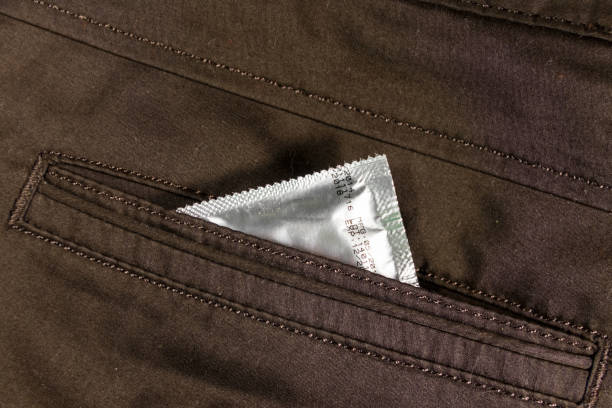презерватив в заднем кармане коричневых брюк - sexual issues aids condom human pregnancy стоковые фото и изображения