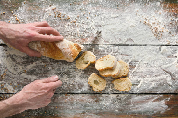 istock Bakery concept background. Hands cutting bread loaf slices 897954622