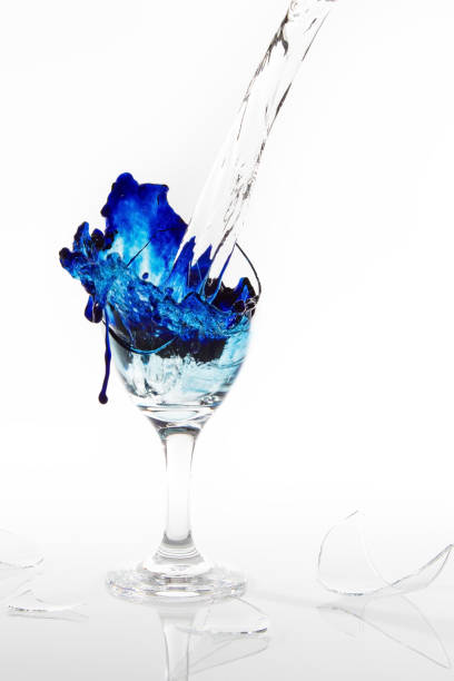 istock Blue water spill from a broken wine glass on a white background 897954728