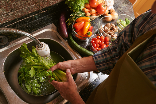 Man washing celery in the kitchen sink, view from above