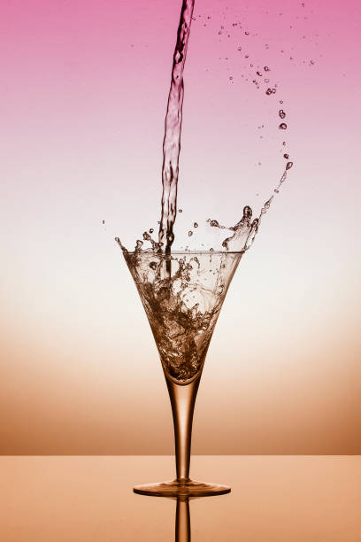 istock Water fall into a glass and splash on a pink and orange background 897958500