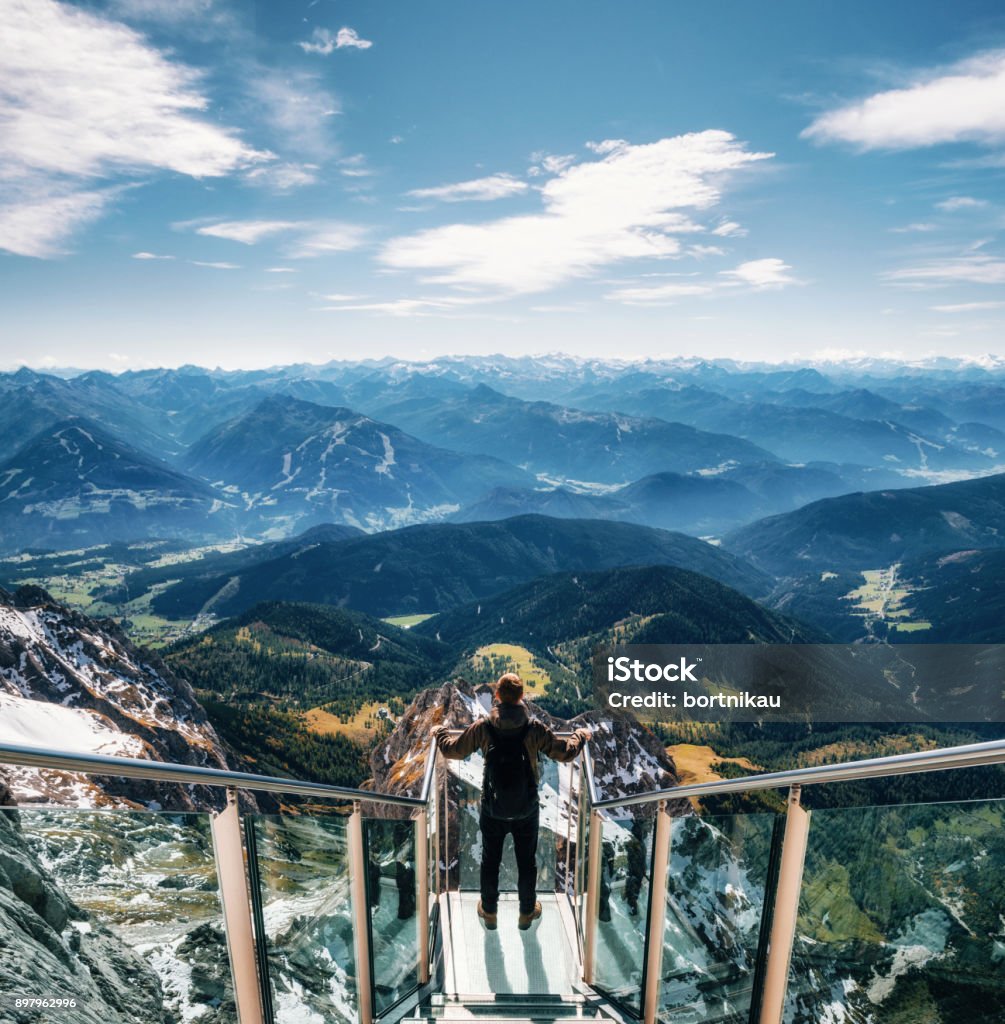 Backpacker at skywalk bridge in Dachstein, Austria Young man with backpack stands on observation deck of skywalk rope bridge Dachstein Mountains and enjoys the landscape in Austria Dachstein Mountains Stock Photo
