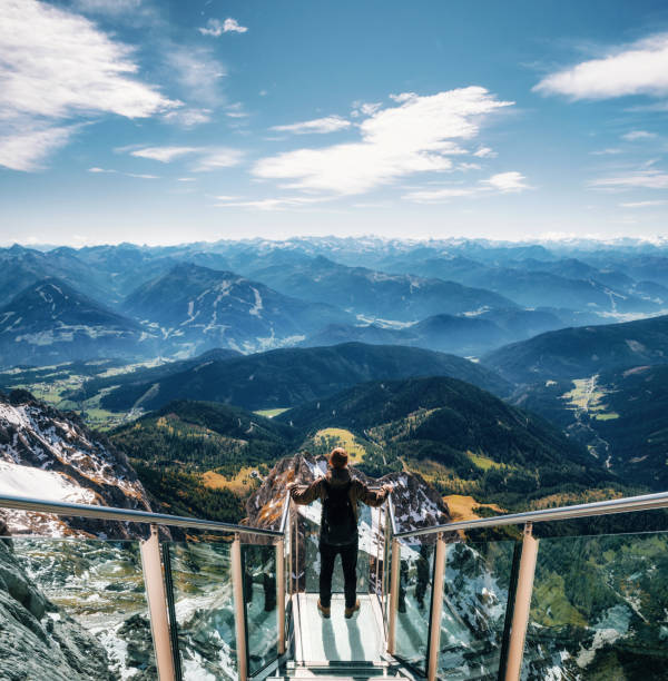 Backpacker at skywalk bridge in Dachstein, Austria Young man with backpack stands on observation deck of skywalk rope bridge Dachstein Mountains and enjoys the landscape in Austria dachstein mountains photos stock pictures, royalty-free photos & images