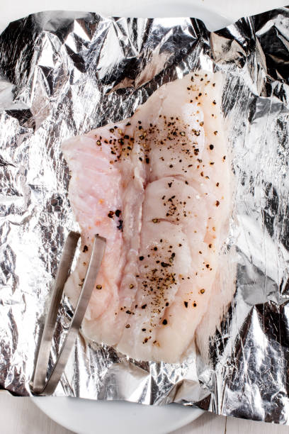 istock raw hake with crushed peppercorn on aluminum foil 897966770