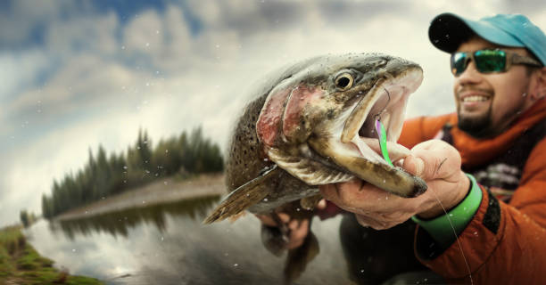 pesca. pescatore e trota. drammatico. - sport fish foto e immagini stock