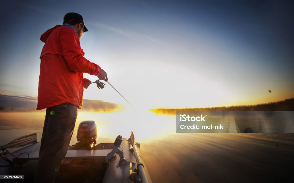 Pesca al atardecer. Hombre pescando en un lago. - Foto de stock de Barco pesquero libre de derechos