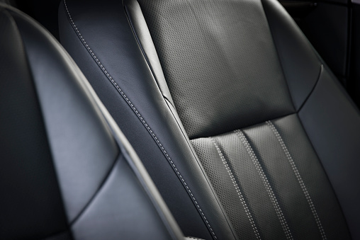Modern luxury car black leather interior. Part of stitched leather car seat details.