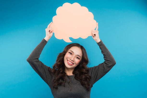 istock Cheerful attractive young woman standing and holding blank speech bubble 897983384