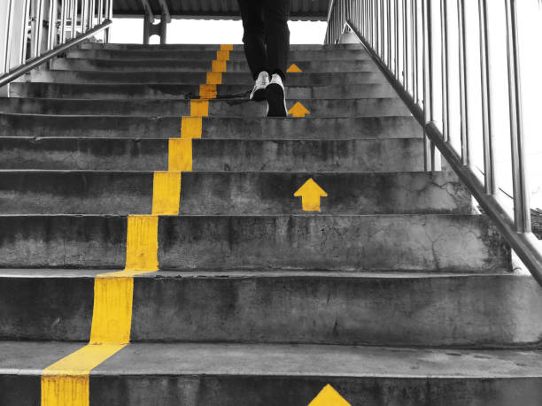 people walking on flyover across the street Looking up to people walking on flyover across the street following yellow arrows direction for safety and being in order. yellow shoes stock pictures, royalty-free photos & images