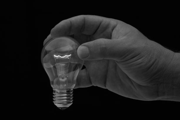 istock Human hand holding a light bulb to conserve energy in darkness artistic conversion 898011826
