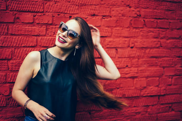 istock Cheerful young woman with beautiful long hair laughing while posing for camera standing against colorful wall with copy space.Emotional happy blogger happy fun during leisure time at urban setting 898011856