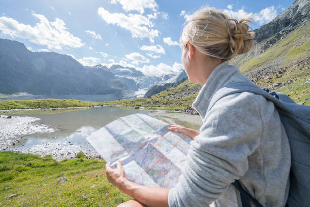 istock Young woman hiker looking at map on mountain trail 898011916