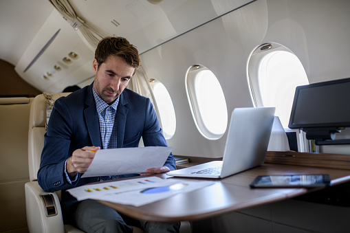 Single man sitting inside private jet airplane and working during the flight.