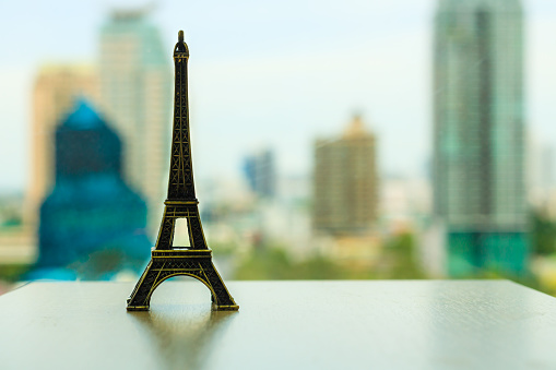 Model of the Eiffel Tower on a table behind cityscape scene in the office. Destination of tourists. Intent to go once.