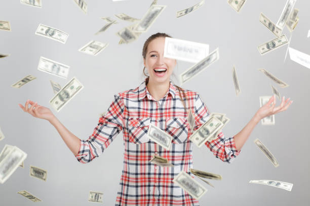 istock happy woman standing under money rain 898057138