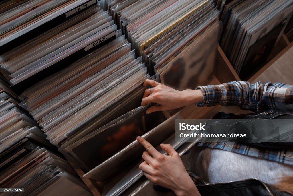 beautiful young woman audiophile is browsing vinyl records in a store Record - Analog Audio Stock Photo