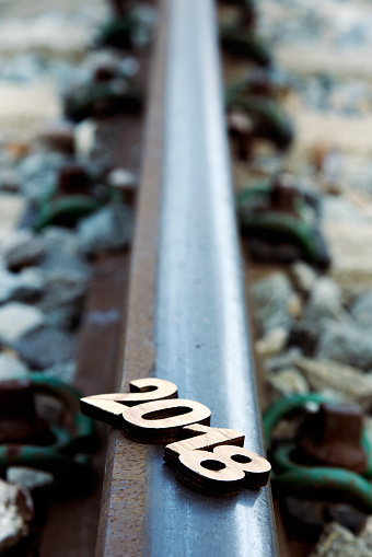 closeup of four wooden numbers forming the number 2018, as the new year, on a rail of a railway, metaphor of the beginning of a new year as a journey
