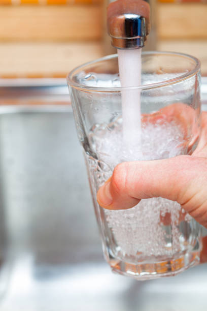 istock Filling up a glass with drinking water from kitchen tap 898069514