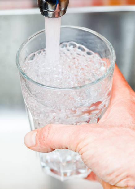 istock Filling up a glass with drinking water from kitchen tap 898069526