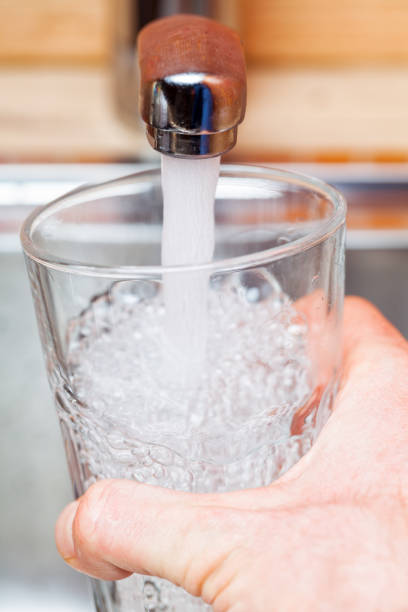 istock Filling up a glass with drinking water from kitchen tap 898069536