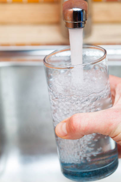 istock Filling up a glass with drinking water from kitchen tap 898069544