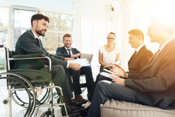 Meeting of disabled people in a bright room with wide windows. Men in wheelchairs businessmen. Meeting of disabled people in a bright room with wide windows. Men in wheelchairs businessmen. Meeting of disabled people in business suits. general manager stock pictures, royalty-free photos & images