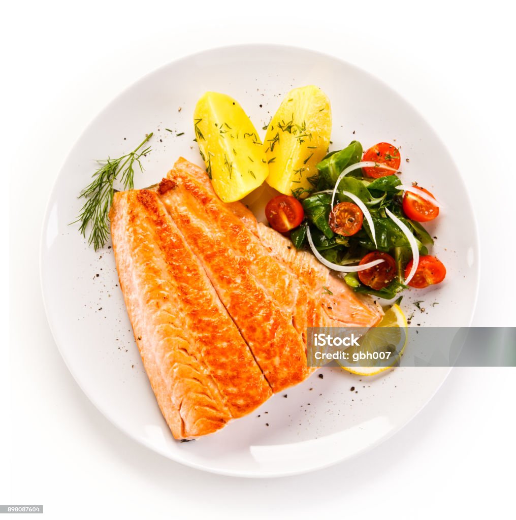 Fish dish - salmon steak and vegetables Fish dish - grilled salmon and vegetables on white background Plate Stock Photo