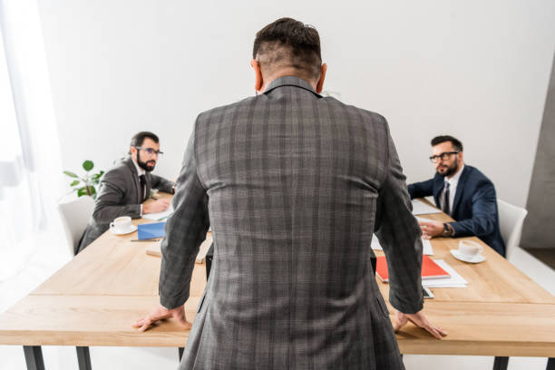 istock rear view of team leader standing and looking at workers 898095486