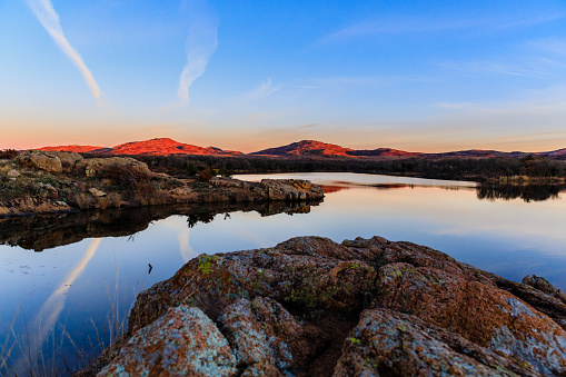 The sky and rocky edge reflects in the still water in the early morning at Wichita Mountains National Wildlife Refuge, November 2017