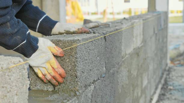 albañil construye muro de ladrillo, vista de cerca en el sitio de construcción - bloque de cemento fotografías e imágenes de stock