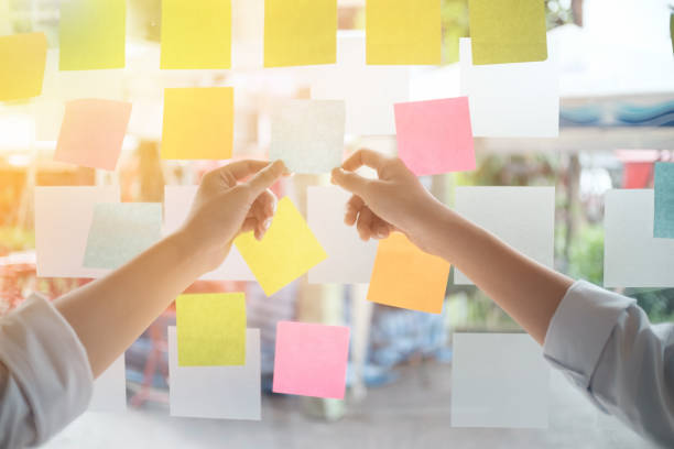 istock Creative business people reading sticky notes on glass wall with colleague working use post it notes to share idea discussing and teamwork, brainstorming concept.Closeup shot. 898131346