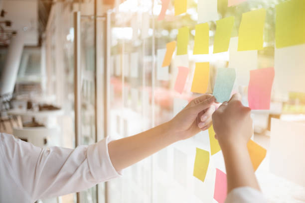 istock Creative business people reading sticky notes on glass wall with colleague working use post it notes to share idea discussing and teamwork, brainstorming concept.Closeup shot. 898133502